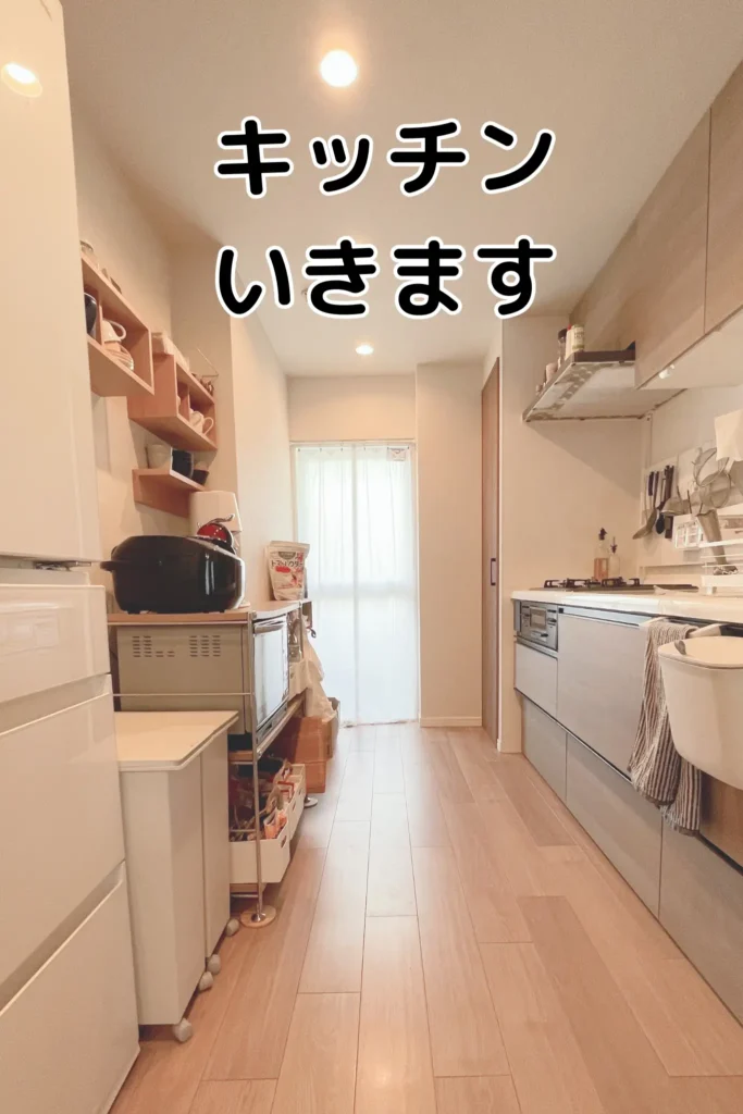 明るく清潔感のある縦長のキッチン空間。壁面収納やワゴンを活用して整理整頓された様子