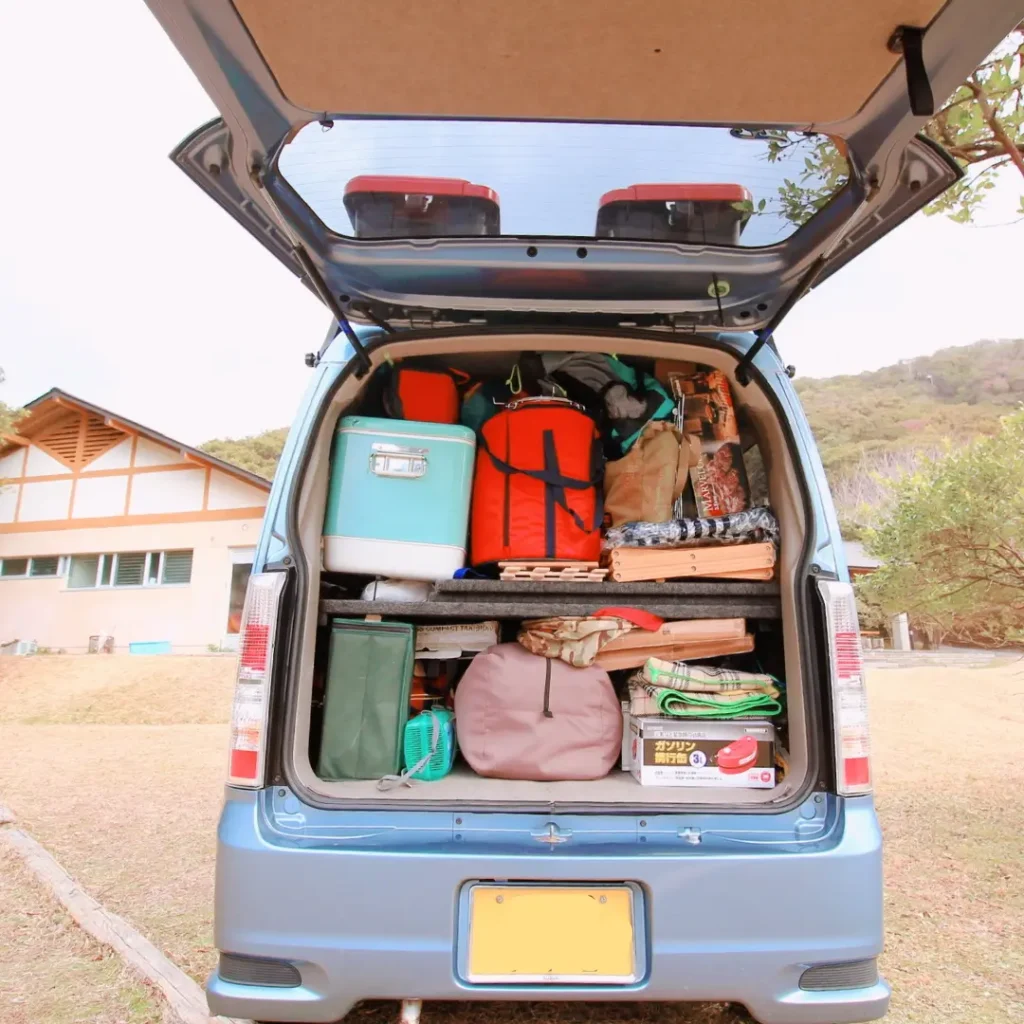 スズキ・エブリイワゴンの荷室いっぱいにキャンプ道具を隙間なく積み込んだ「テトリス収納」の実例写真。クーラーボックスや収納コンテナ、キャンプ用品がパズルのように積まれている様子。